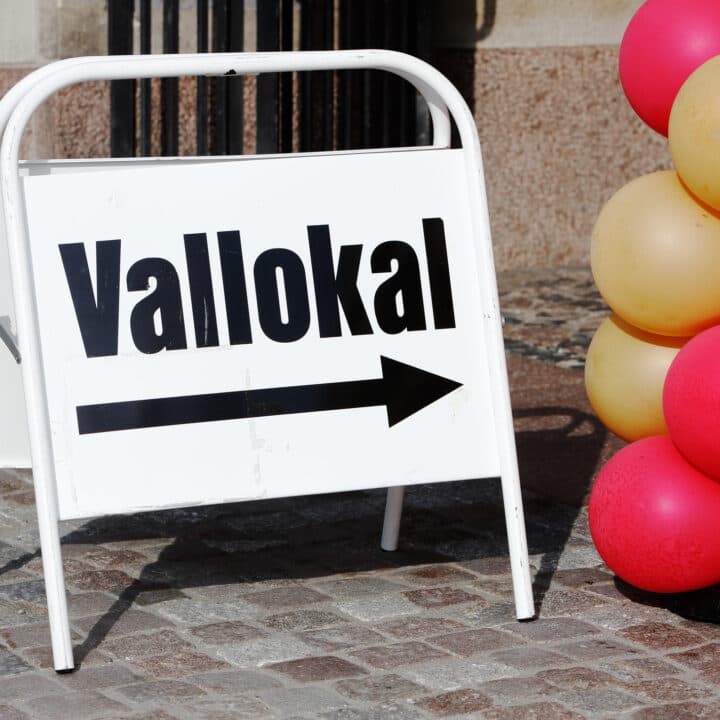 Portable directional sign with text in Swedish to a polling station in use for general election.